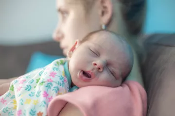 bébé endormi sur l'épaule de sa maman soucieuse